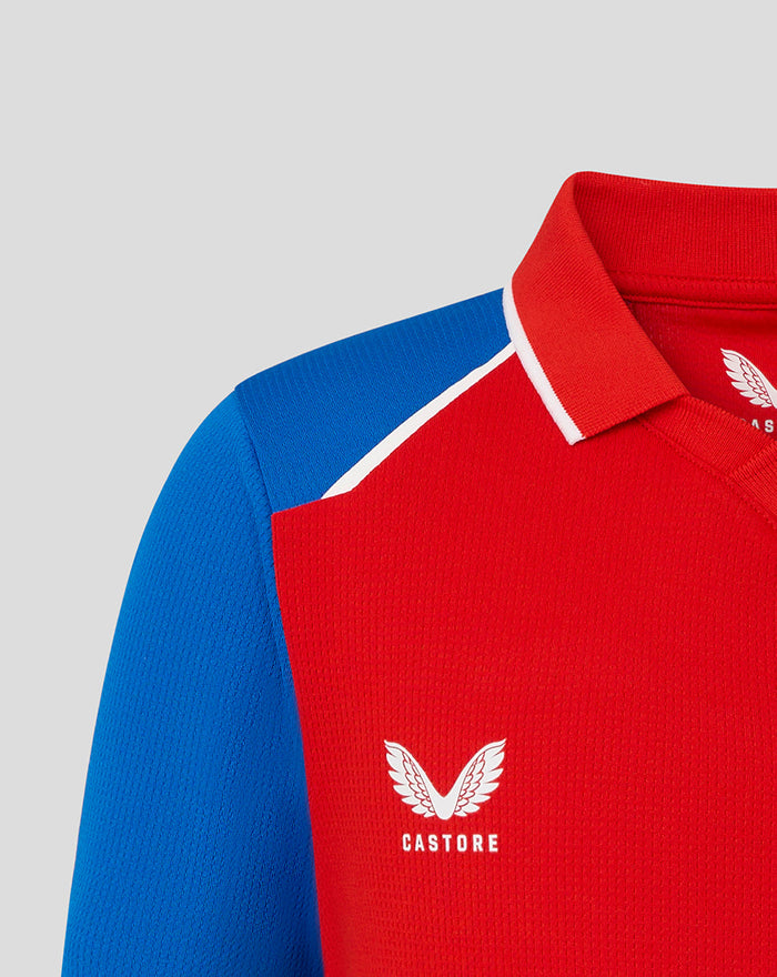 Close up of red junior T20 shirt with blue shoulder panel and white piping, featuring the England crest and Castore logo.