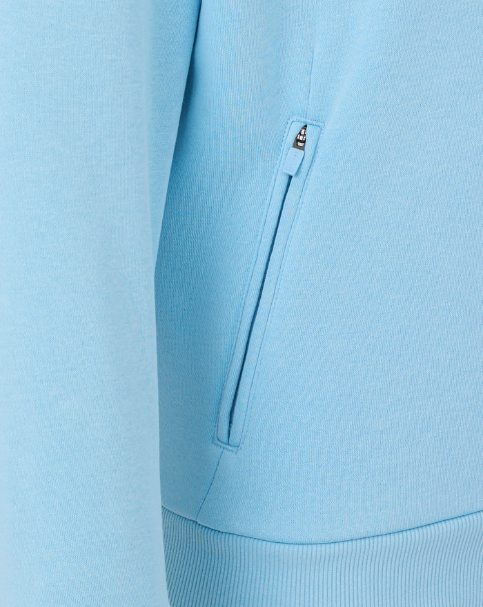 Close up of a light blue hoodie showing a vertical zip pocket detail