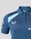 Close-up of the polo chest showing Castore branding and navy England crest on blue fabric.