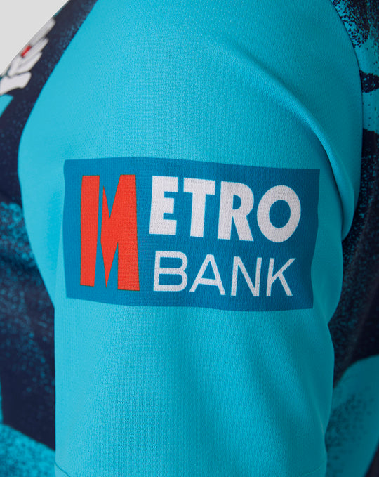 Close up of turquoise cricket jersey sleeve with Metro Bank sponsor patch