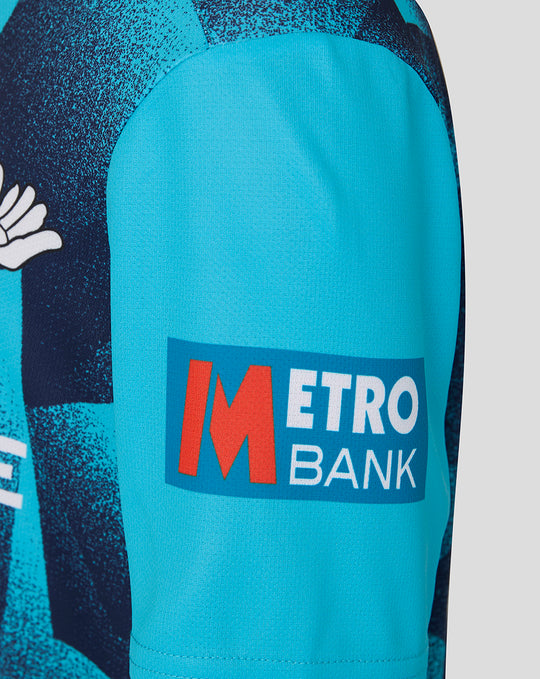 Close-up of bright blue sleeve with Metro Bank patch on the Junior 26/27 OD Short Sleeve Jersey Aqiarius.