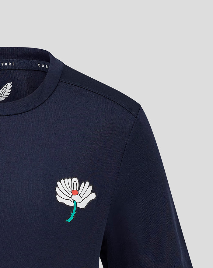 Navy juniors training tee with a large white floral emblem on the left chest.