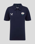 Front view of navy juniors polo with Castore wing logo on the left chest and a white flower emblem on the right chest.