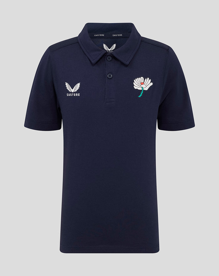 Front view of navy juniors polo with Castore wing logo on the left chest and a white flower emblem on the right chest.