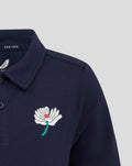 Navy juniors polo with a white flower crest on the left chest and a Castore label at the collar.