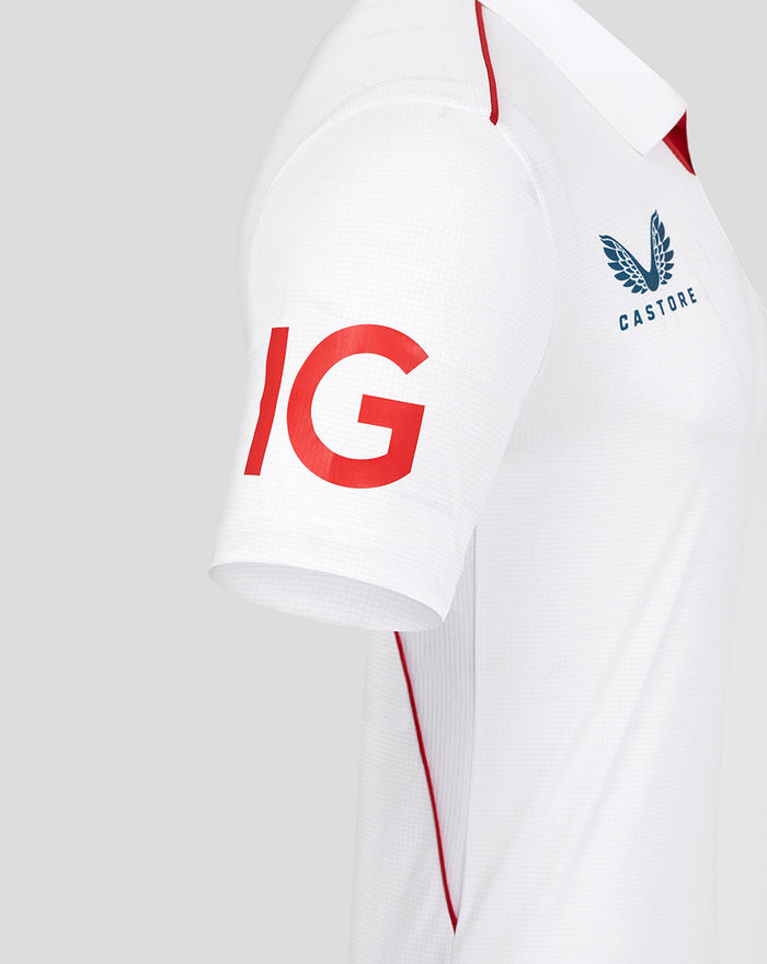 Close-up of white cricket shirt sleeve with bold red IG lettering and red piping along the side.