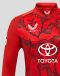 Close up of red T20 Pro long sleeve shirt featuring bold graphic print Three Lions crest and Toyota logo.