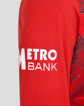 Red ECB Men's 25/26 T20 sweater sleeve with white Metro Bank branding.