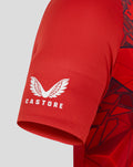 Red replica World Cup shirt fabric with a white wing crest and Castore branding at the hem