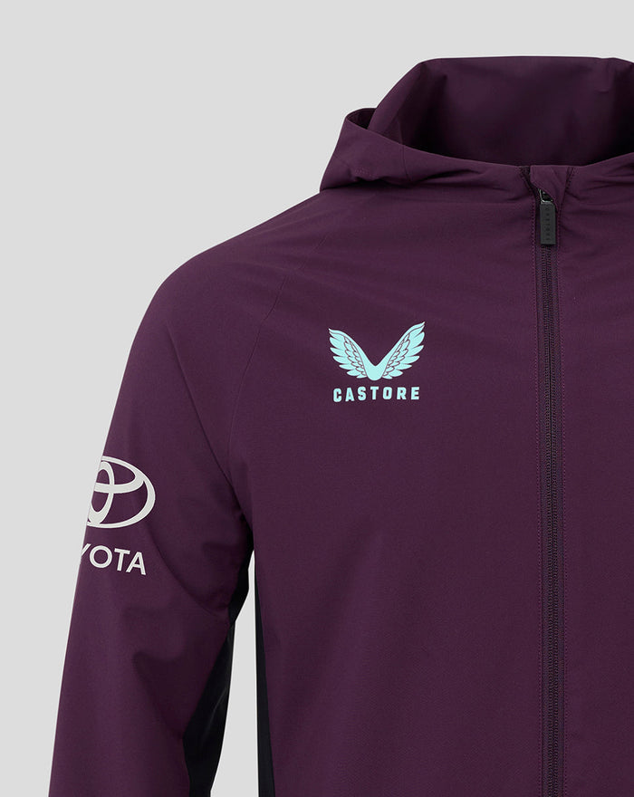 Purple training rain jacket close-up highlighting a pale blue crest logo on the chest and front zipper with hood.