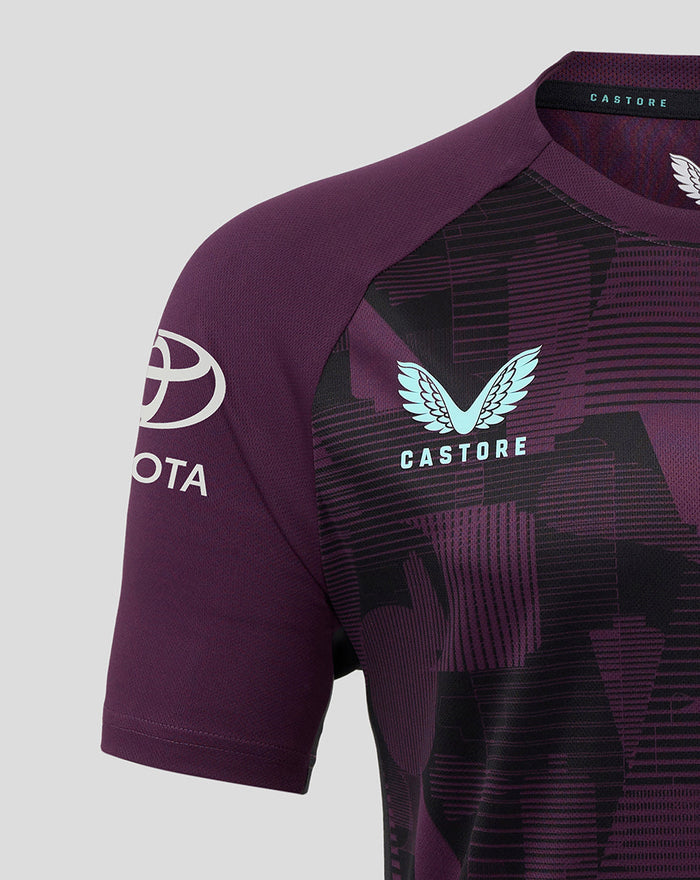 Shoulder close up of blackberry wine training tee with light blue Castore logo and bold geometric pattern on the chest
