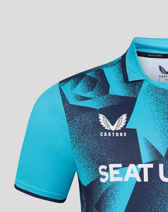Turquoise Yorkshire T20 jersey close-up showing a white flower crest on the chest and Castore branding