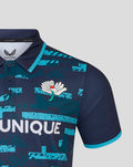 Close up of navy jersey chest showing white flower crest and turquoise abstract print with turquoise sleeve edge