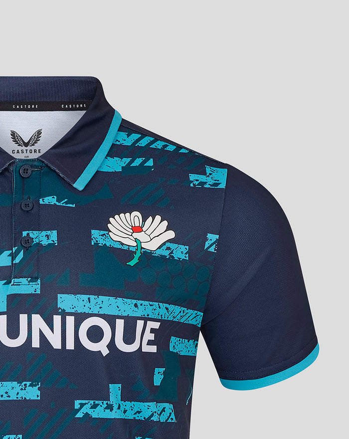 Close up of navy jersey chest showing white flower crest and turquoise abstract print with turquoise sleeve edge