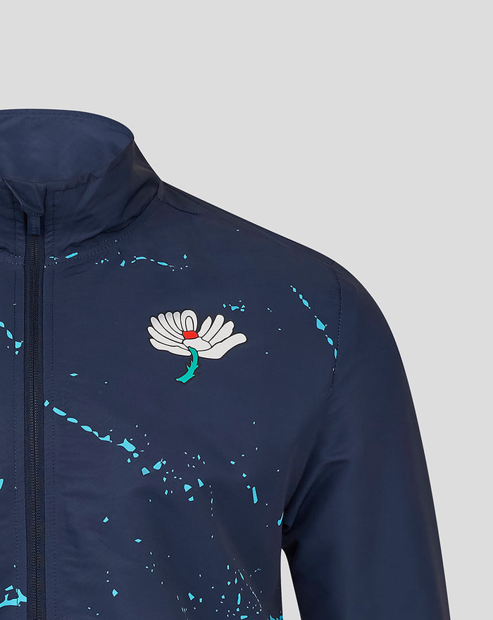 Navy track jacket with zip front high collar turquoise paint splatters and a white floral crest on the chest