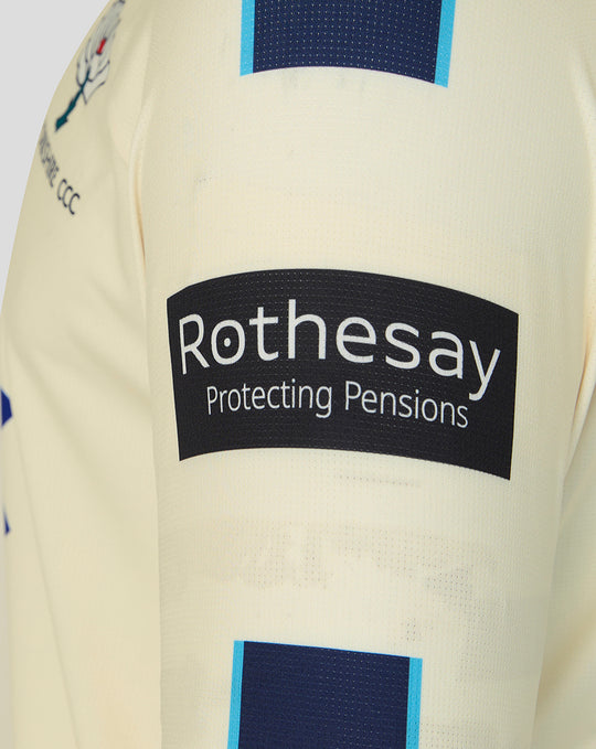 Cream long sleeve cricket jersey with Rothesay sponsor patch and blue block details