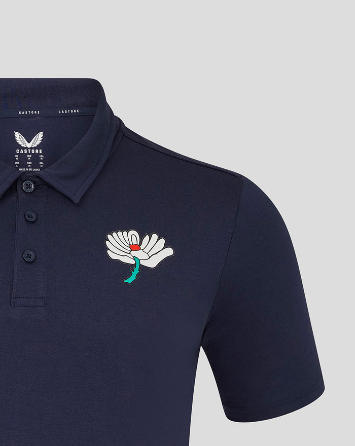 Navy Yorkshire polo with large white floral crest on left chest and teal stem