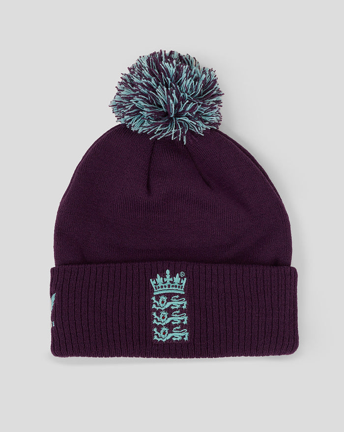 Purple knit bobble hat with a teal faux fur pom and crest embroidered on the cuff